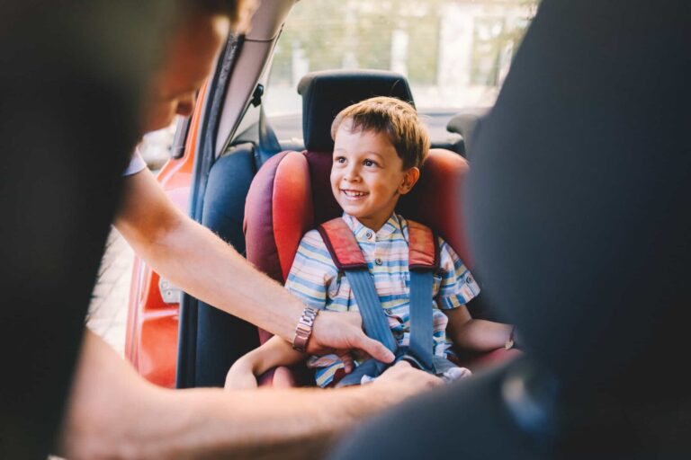 Arrangements For Children: Father securing child in car seat. Child safety is paramount. Clairs Keeley Lawyers, Perth Family Law.