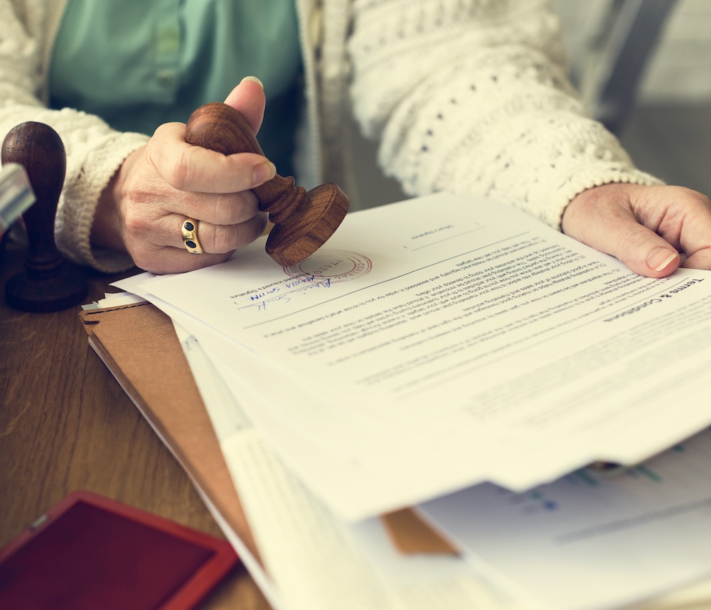 Grant of Probate in Perth: Hand stamping signed will & probate paperwork. Clairs Keeley Lawyers specializing in Estates, Wills, & Commercial Law.