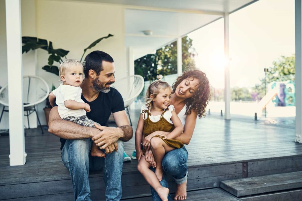 Happy family of four on porch, Perth. Parents with children at home. Family Dispute Resolution in Perth. Happy resolution for families.